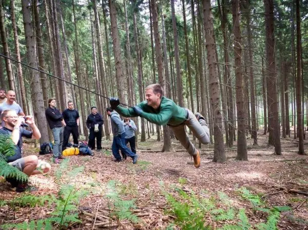 Mann überquert selbstgebaute Seilbrücke in einem Waldgebiet