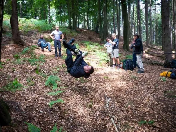 Mann überquert selbstgebaute Seilbrücke, während andere zuschauen