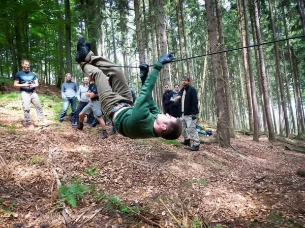 Mann überquert selbstgebaute Seilbrücke zwischen Bäumen im Wald