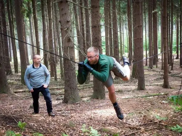 Mann überquert selbstgebaute Seilbrücke zwischen Bäumen im Wald