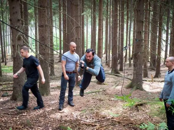 Mann überquert selbstgebaute Seilbrücke zwischen Bäumen im Wald