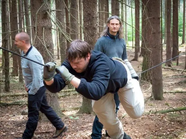 Mann überquert selbstgebaute Seilbrücke zwischen Bäumen im Wald