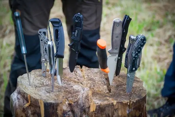 Mehrere Messer stecken in einem Holzscheit, verschiedene Klingenformen erkennbar