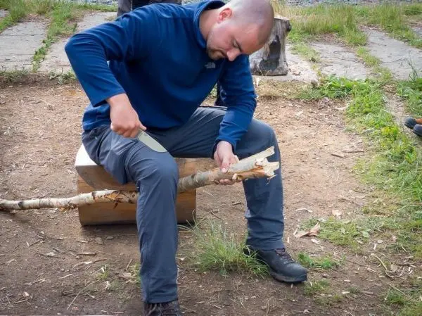 Messer bearbeitet einen Holzstock auf einer Sitzfläche