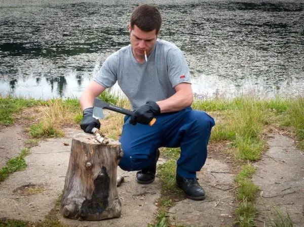 Messer bearbeitet Holzstück auf einem Baumstumpf am Wasser