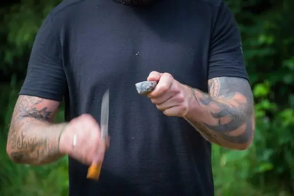 Messer schneidet in einen Steinblock, während die andere Hand stabilisiert