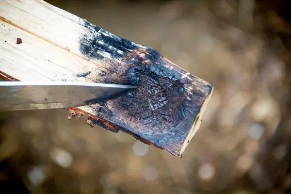 Messer schneidet in verbranntes Holzstück mit Kerben