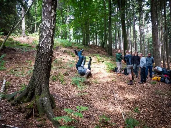 Person macht einen Handstand im Wald, Gruppe beobachtet sie