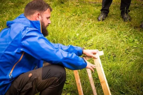 Person misst eine Holzlatte auf dem Boden