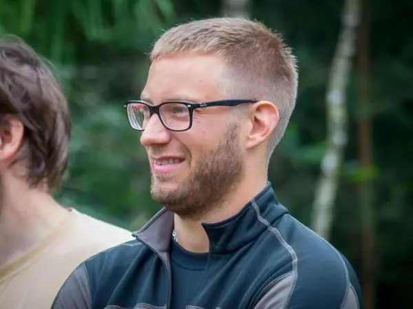 Person mit Brille lächelt und steht im Freien