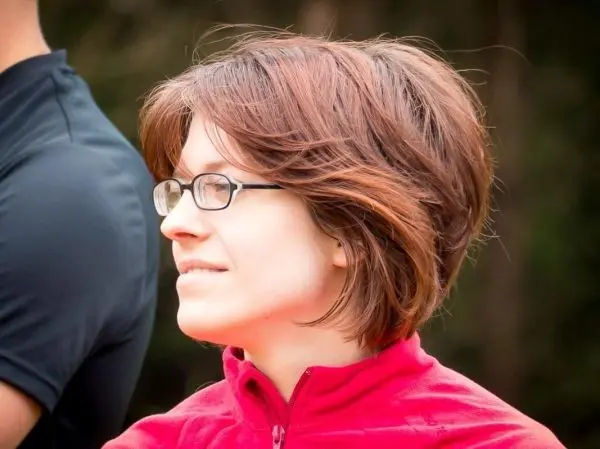 Person mit Brille und rotem Oberteil steht seitlich und schaut nach vorne