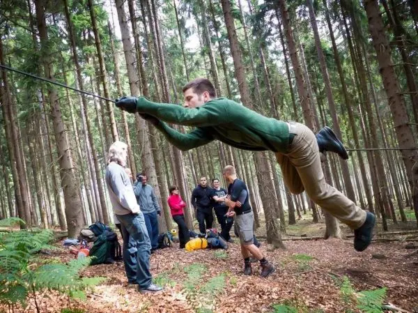 Person schwingt an einem Seil zwischen Bäumen beim Überlebenstraining
