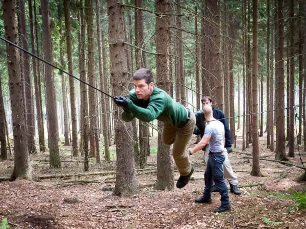 Person schwingt an einem Seil zwischen Bäumen im Wald
