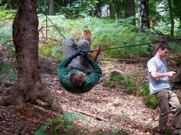 Person schwingt an Seil zwischen Bäumen im Wald