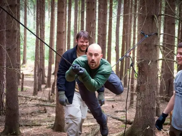 Person schwingt an Seil zwischen Bäumen im Wald