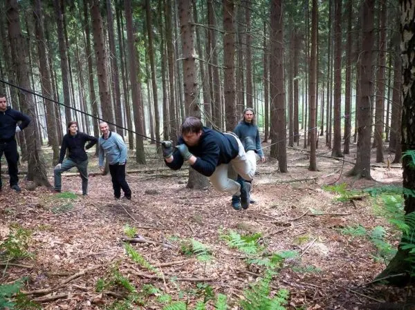 Person schwingt an Seil zwischen Bäumen im Wald beim Survival Training