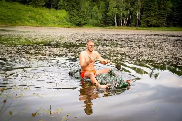 Person sitzt auf einem selbstgebauten Floß im Wasser