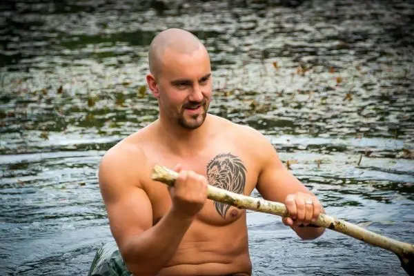 Person sitzt im Wasser und hält einen Stock in der Hand