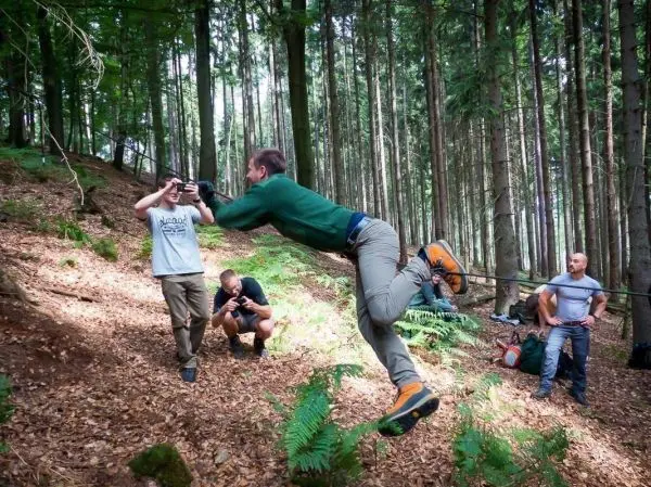 Person springt über eine selbstgebaute Seilbrücke im Wald