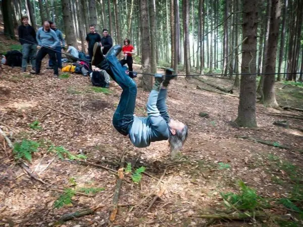 Person überquert selbstgebaute Seilbrücke zwischen Bäumen im Wald