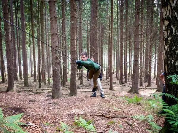 Person zieht an einem Seil zwischen Bäumen im Wald