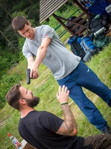 Person zielt mit einer Pistole auf eine sitzende Person beim Training