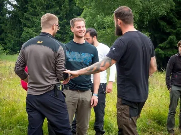 Personen stehen im Gespräch auf einer Wiese beim Überlebenstraining