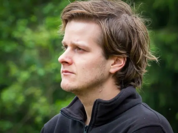 Porträt eines Mannes mit kurzem, lockigem Haar in einem dunklen Pullover