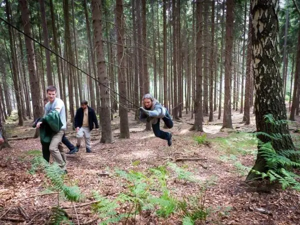 Selbstgebaute Seilquerung wird von einer Person überquert, während andere helfen