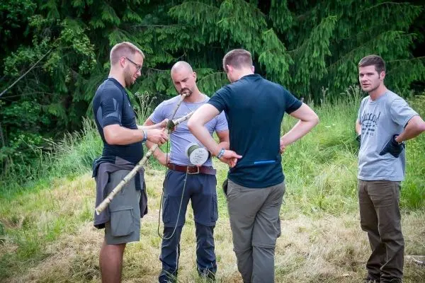 Vier Personen betrachten gemeinsam eine selbstgebaute Konstruktion aus Holz und Seil