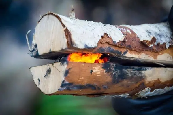 Zunder glimmt zwischen zwei Holzstücken