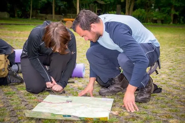 Zwei Personen analysieren eine Karte auf dem Boden und markieren Punkte