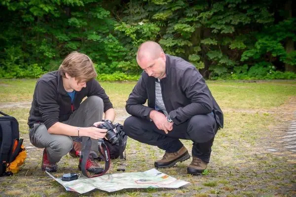 Zwei Personen betrachten eine Karte und eine Kamera auf dem Boden