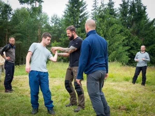 Zwei Personen demonstrieren eine Technik zur Selbstverteidigung im Freien