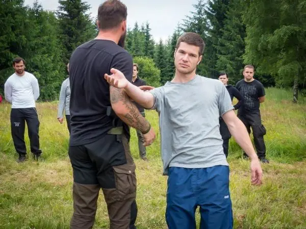 Zwei Personen demonstrieren eine Technik zur Selbstverteidigung in einer Wiese