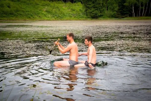 Zwei Personen knien im Wasser und halten einen Stock über der Wasseroberfläche