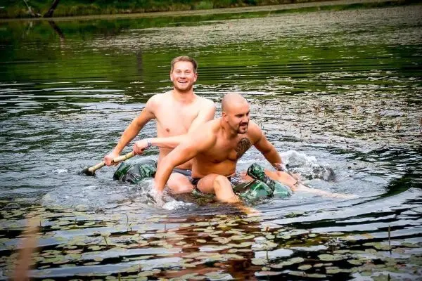 Zwei Personen paddeln auf einem improvisierten Floß durch einen See