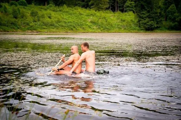 Zwei Personen paddeln auf einem improvisierten Floß über einen See