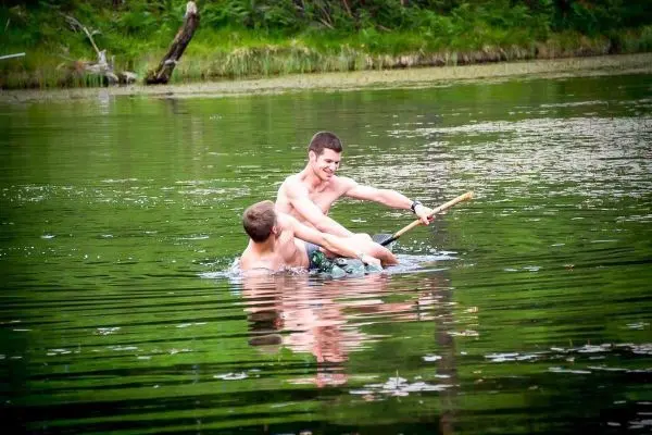 Zwei Personen paddeln mit einem Stock in einem Gewässer