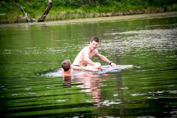 Zwei Personen sitzen auf einem Holzbrett im Wasser