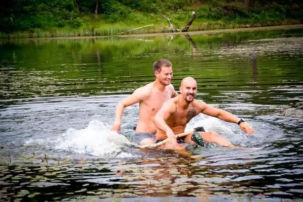 Zwei Personen sitzen auf einem schwimmenden Objekt im Wasser und spritzen