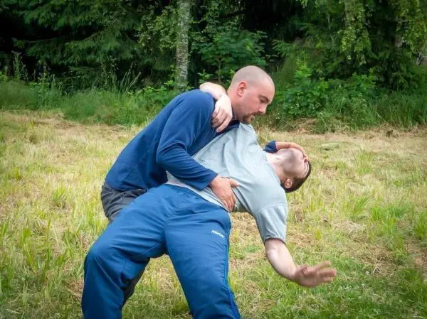Zwei Personen üben eine Selbstverteidigungstechnik auf einer Wiese