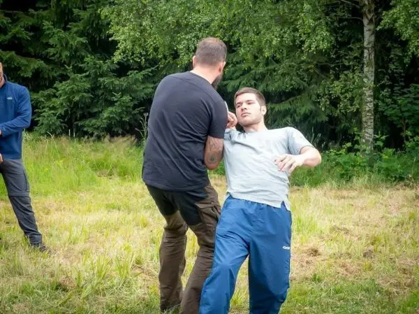 Zwei Personen üben eine Selbstverteidigungstechnik auf einer Wiese