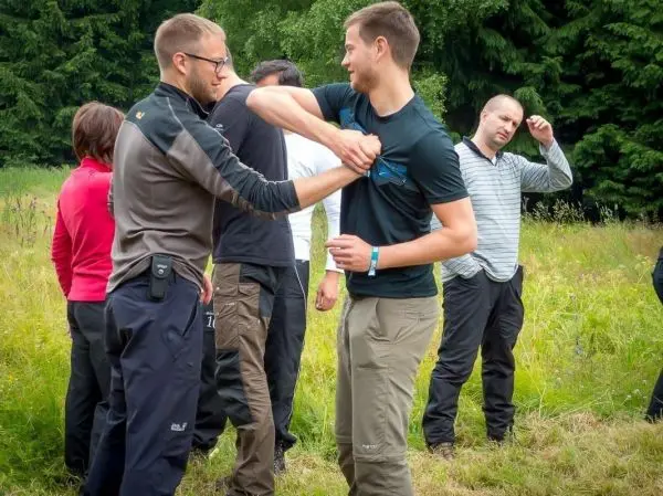 Zwei Personen üben eine Selbstverteidigungstechnik im Freien auf einer Wiese