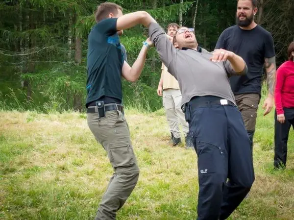 Zwei Personen üben eine Selbstverteidigungstechnik im Freien auf einer Wiese