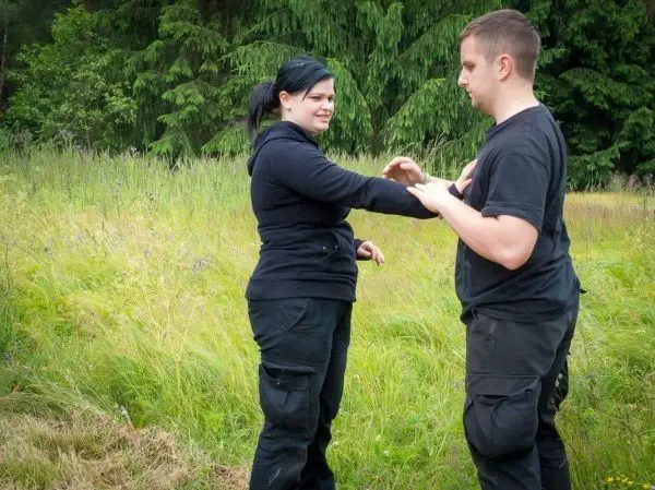 Zwei Personen üben eine Selbstverteidigungstechnik im Freien auf einer Wiese