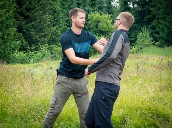 Zwei Personen üben eine Selbstverteidigungstechnik in einer Wiese