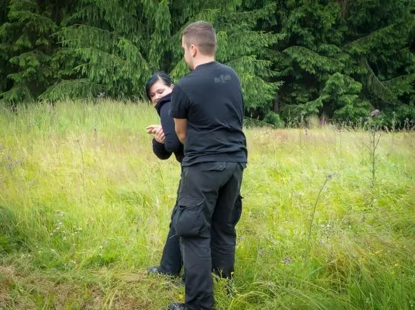 Zwei Personen üben eine Selbstverteidigungstechnik in einer Wiese