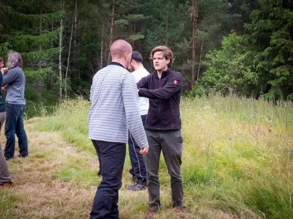 Zwei Personen üben eine Technik im Freien auf einer Wiese