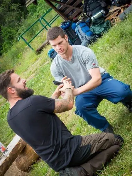 Zwei Personen üben eine Technik zur Handentwaffnung im Freien